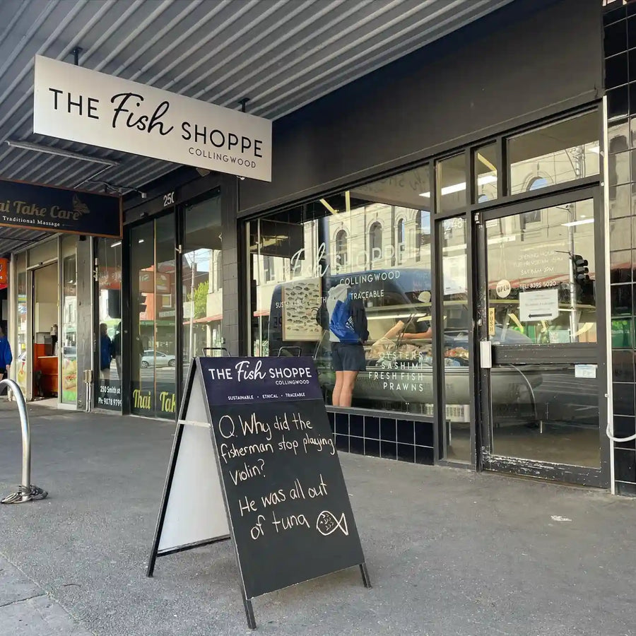 The Fish Shoppe in Collingwood storefront with a large white hanging sign, glass windows, and a black A-frame chalkboard sign on the sidewalk.