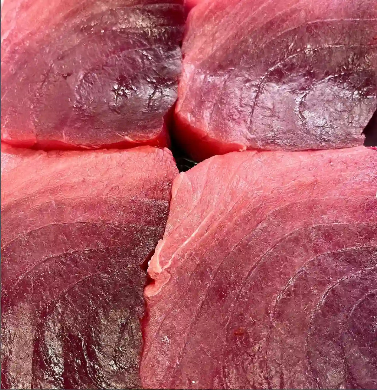 Close-up of raw tuna fish fillets showing the deep red muscle texture and natural marbling.